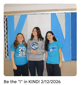 Students taking a picture in front of KIND bulletin board