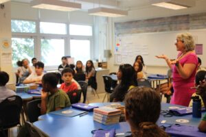 Ms. Schwach in her classroom talking to incoming class